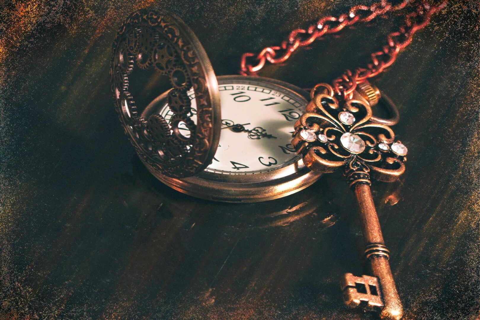 A key and a pocket watch on top of a table.