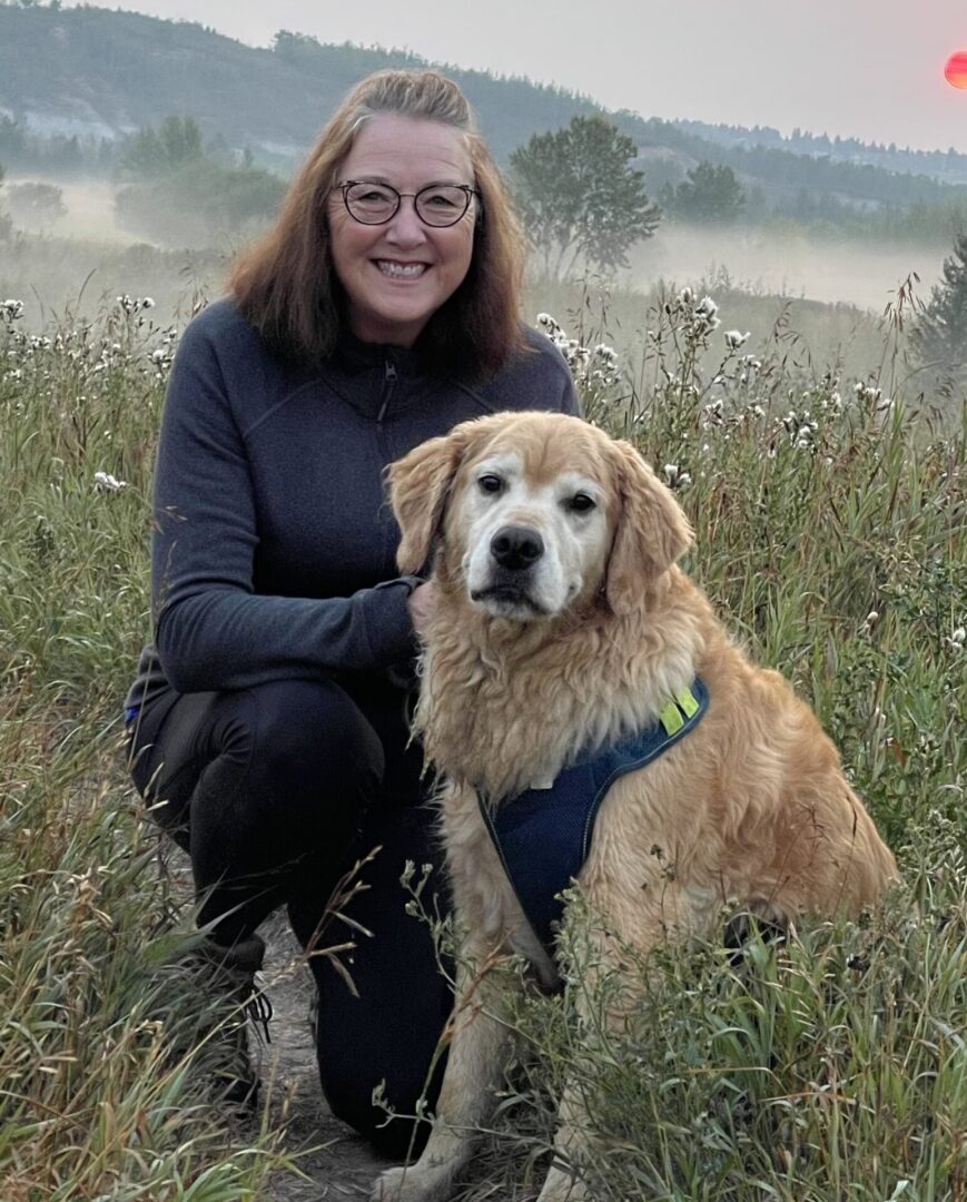 A woman and her dog in the grass.