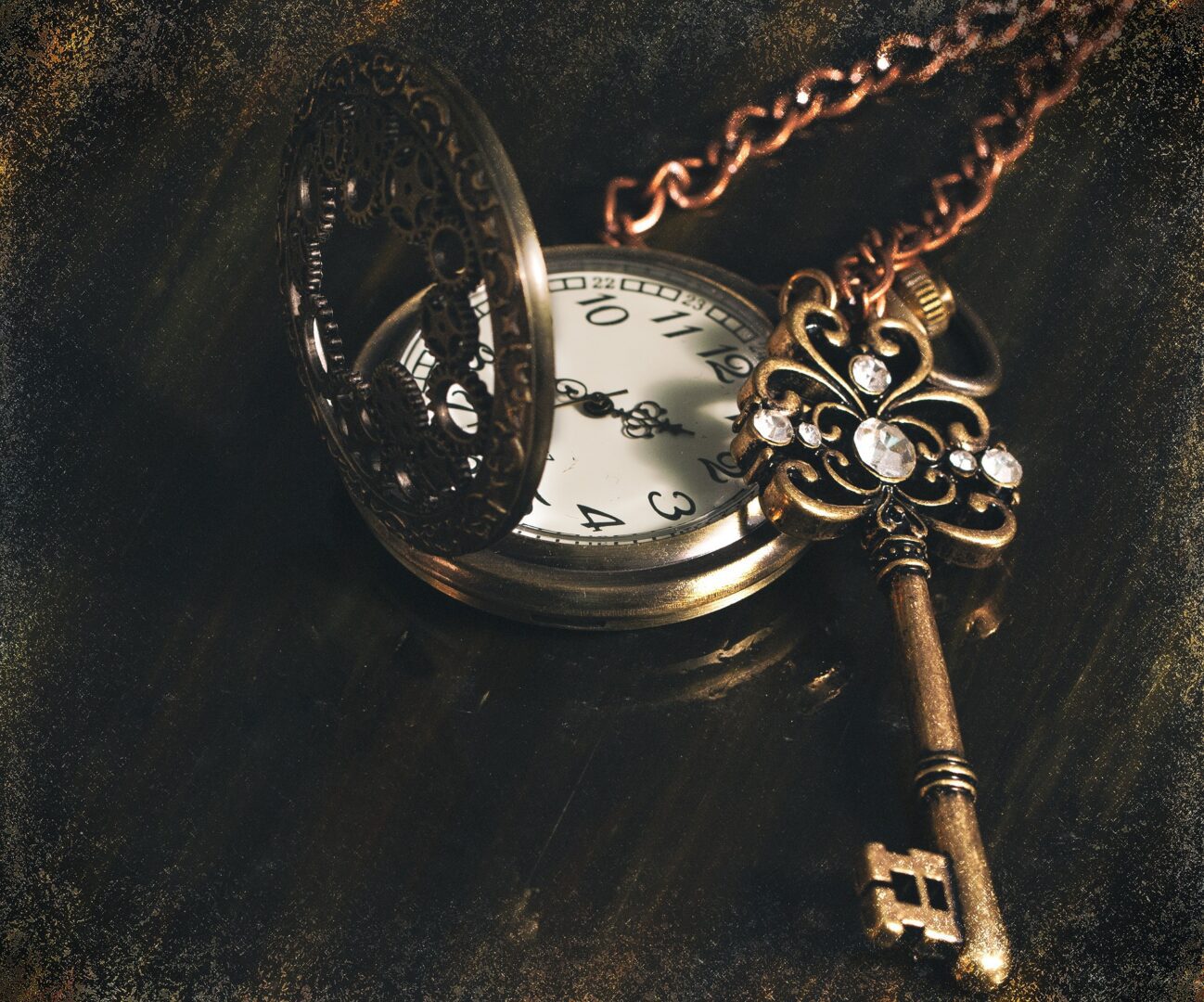 A pocket watch and key on top of a table.